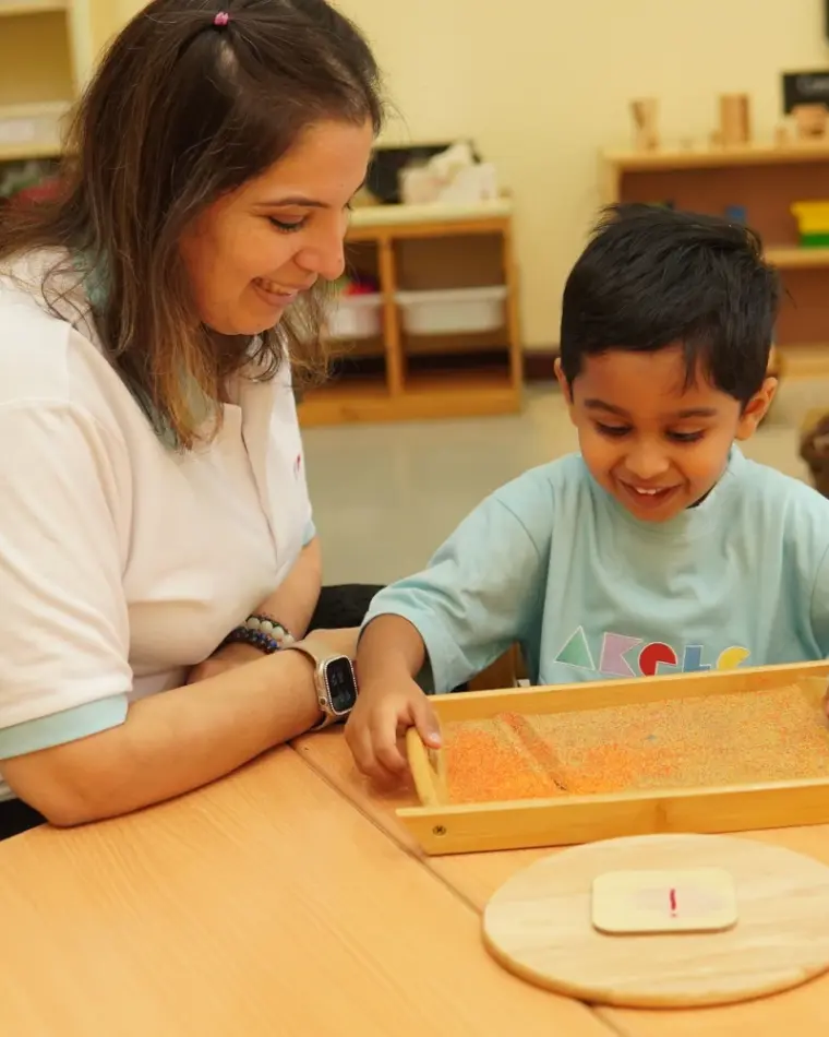 Teacher and toddlers at the sand and sensory table in natural light